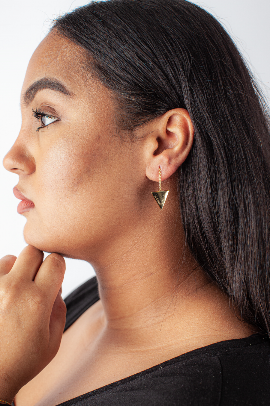 Woman showing off gold triangular empowering earrings