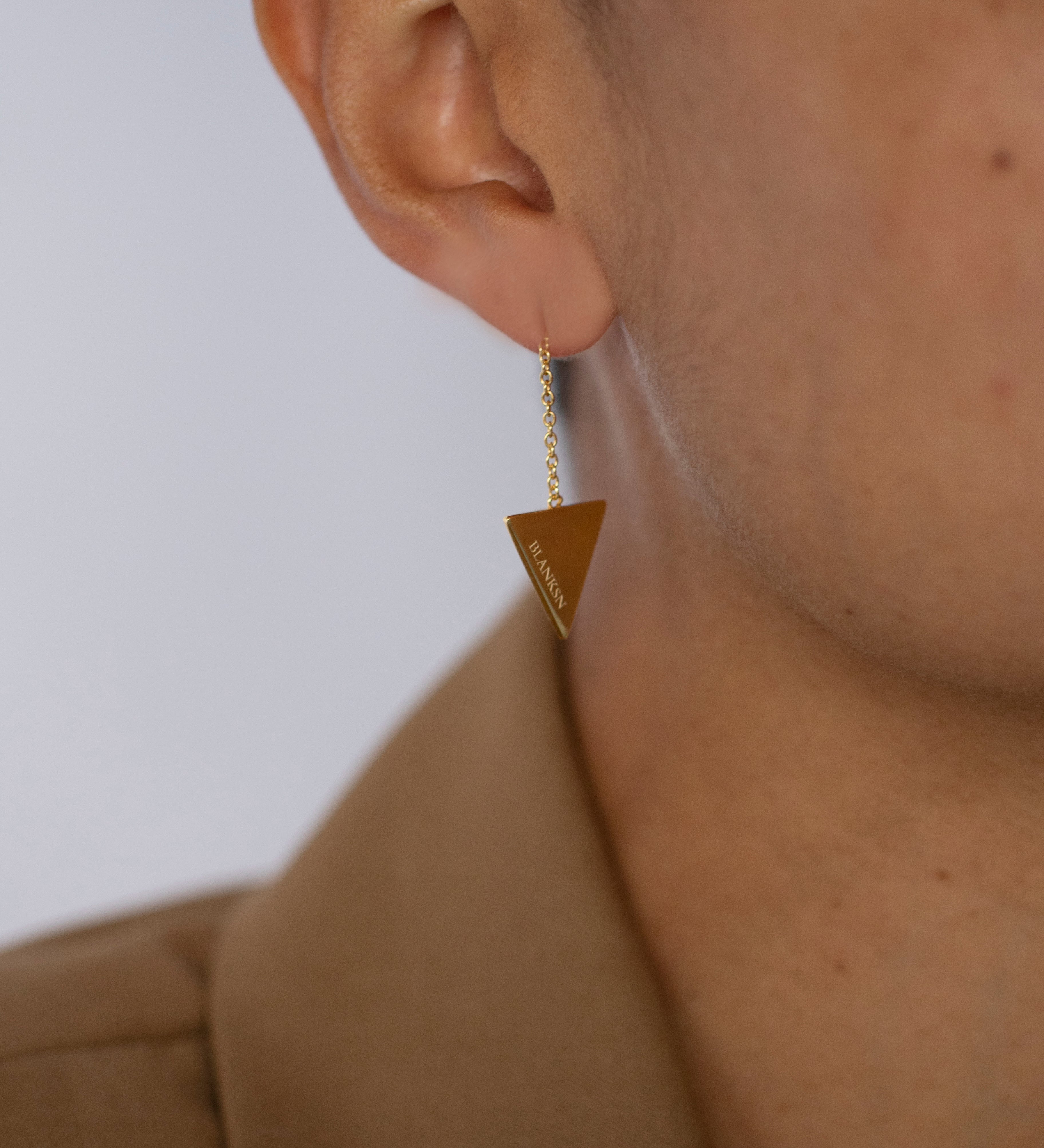 Woman wearing gold triangular empowering earrings