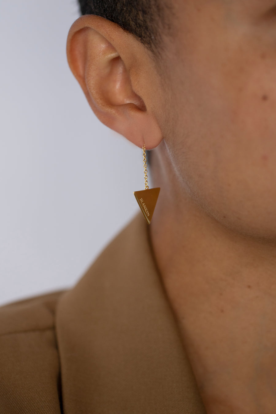 Woman wearing gold triangular empowering earrings